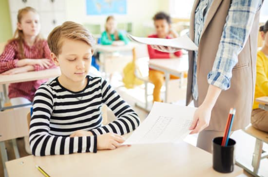 Customized Assessments Teacher handing exams to students